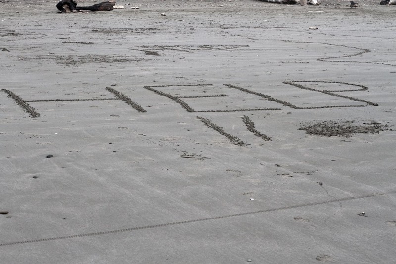 Help written on beach. An offer or a plea? Who can say?